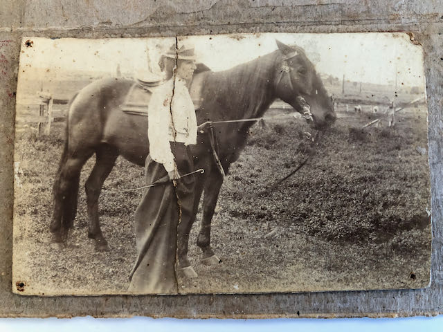 Undated photo of Mary Ann Madden standing beside a horse wearing a hat, white blouse and long skirt.